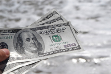 Girl holding money bill of 300 dollars on background of sea ocean