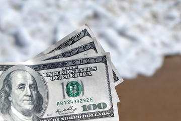 Girl holding money bill of 300 dollars on background of sea ocean