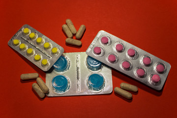 Pharmaceuticals antibiotics medicine pills, colorful antibacterial pills on red background, natural...