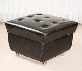 vintage black leather stool in a living room, retro 70s