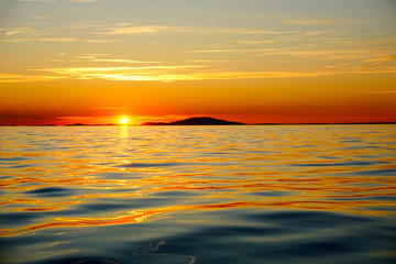 Naklejka na ściany i meble Orange and gold color tone beautiful sunset above the golden and blue sea surface on the island at the summer