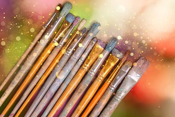 A row of artist paint brushes on abstract background