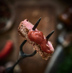 Slices of Medium rare grilled Steak Ribeye on meat fork. Juicy piece of meat on a fork