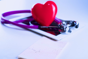 Medical stethoscope and a red heart and tablet with cardiogram on white background. Technology...