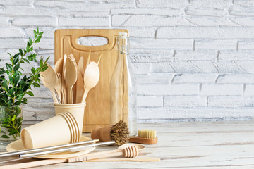 Eco-friendly kitchenware on wooden background over white brick wall. . Tableware, brushes, spoons...