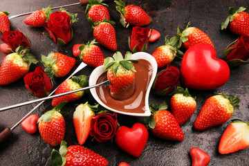 Valentine Chocolate fondue melted with fresh strawberries and dark and white chocolate. Red roses and sugar hearts for Valentines Day. Valentine Background