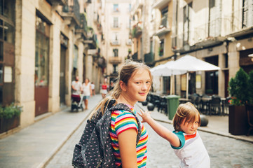 Outdoor portrait of pretty teenage girl with annoying little brother