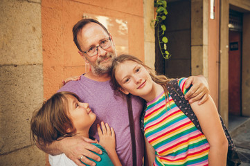 Outdoor portrait of happy father with young kids