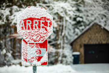 A selective focus shot of a French Canadian traffic control sign saying stop, covered with snow and...
