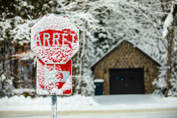 French Canadian traffic and highway signs are barely readable after a heavy winter snowstorm,...