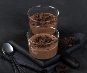 Italian dessert chocolate Panna cotta with chocolate pieces in a glass Cup on a dark background