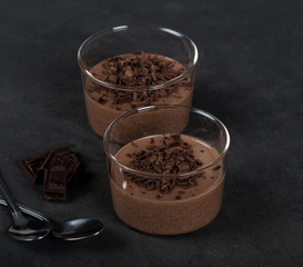 Italian dessert chocolate Panna cotta with chocolate pieces in a glass Cup on a dark background