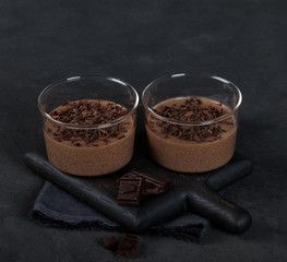 Italian dessert chocolate Panna cotta with chocolate pieces in a glass Cup on a dark background