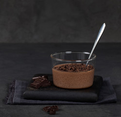 Fototapeta na wymiar Italian dessert chocolate Panna cotta with chocolate pieces in a glass Cup on a dark background