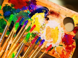 Paintbrush in art paint on wooden palette