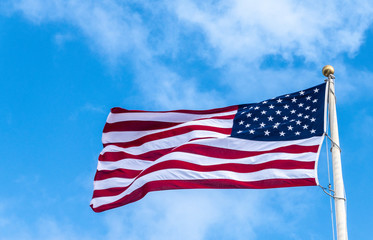 Oahu, Hawaii, USA. - January 10, 2020: Pearl Harbor. Closeup of flying American flag against blue sky with some minor white clouds.