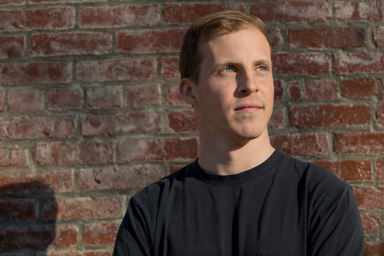 caucasian millennial male construction worker in front of brick wall