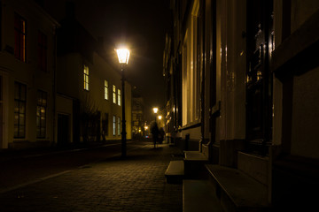 Fototapeta na wymiar Utrecht, Netherlands, January 21st, 2020.. Misty Evening, night view of street, old dutch houses, pedestrian, bicycles along the street.