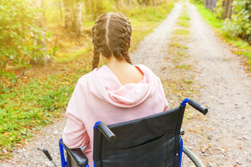 Young happy handicap woman in wheelchair on road in hospital park waiting for patient services....