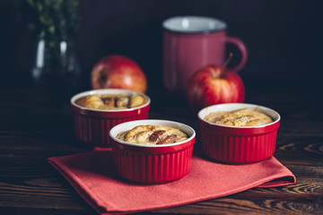 Apple pie in ceramic baking molds ramekin on dark wooden table. Close up, shallow depth of the field.