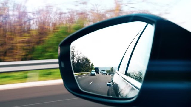 Cinematic 4k UHD View in car rear view mirror of a new limousine with multiple cars and trucks driving fast on French highway autoroute during peak pollution 