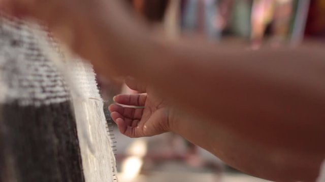  indigenous Argentine woman weaves a poncho on loom with handmade wool