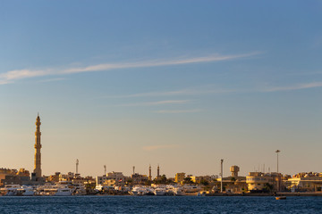 Fototapeta na wymiar Hurghada, Egypt, a city at sunset. View of the ancient city from the red sea. Panoramic view. A port with ships and a residential area with a mosque.