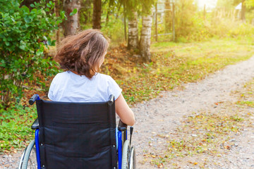 Young happy handicap woman in wheelchair on road in hospital park enjoying freedom. Paralyzed girl...