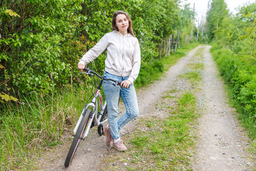 Young woman riding bicycle in summer city park outdoors. Active people. Hipster girl relax and...
