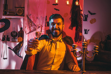 Happy Halloween. A glass of wine in the hand of an attractive man. Halloween party. Vampire is a ghost. A terrible holiday in October.