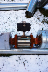 Discarded old insulated hot water pipe with valve on snow