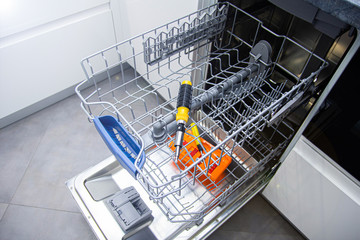 repair of a modern dishwasher with screwdrivers in the kitchen