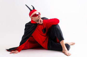 Fashionable man in black red  carnival costume wearing devil horns and sportive sunglasses and...