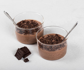 Italian dessert chocolate Panna cotta with chocolate pieces in a glass Cup on a light background