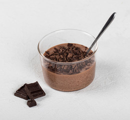 Italian dessert chocolate Panna cotta with chocolate pieces in a glass Cup on a light background