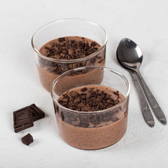 Italian dessert chocolate Panna cotta with chocolate pieces in a glass Cup on a light background