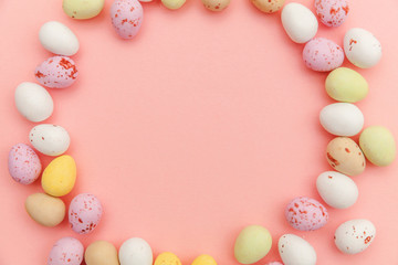 Happy Easter concept. Preparation for holiday. Easter candy chocolate eggs and jellybean sweets isolated on trendy pastel pink background. Simple minimalism flat lay top view copy space