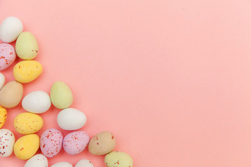 Fototapeta na wymiar Happy Easter concept. Preparation for holiday. Easter candy chocolate eggs and jellybean sweets isolated on trendy pastel pink background. Simple minimalism flat lay top view copy space