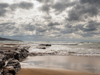 Ocean wave reaching sandy beach, Fanore, county Clare Ireland. Sunny summer day. Nobody. Cloudy blue sky.