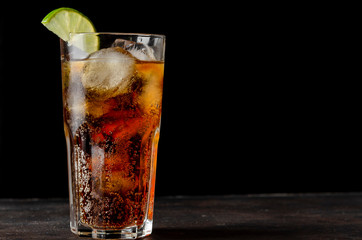 soda or cocktail with ice on table against black background