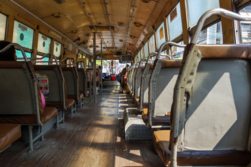 Interior view of corridor between row of seats in old local hot public transportation bus without air condition in Bangkok, Thailand.