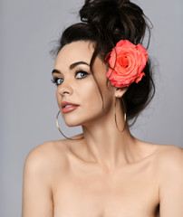 Obraz premium Portrait of young beautiful sexy brunette naked woman in circle earrings with rose in hair