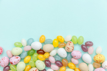 Fototapeta na wymiar Happy Easter concept. Preparation for holiday. Easter candy chocolate eggs and jellybean sweets isolated on trendy pastel blue background. Simple minimalism flat lay top view copy space.