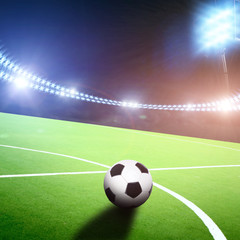 Fototapeta premium Boisko do piłki nożnej z piłką na stadionie ze światłami i błyskami w nocy