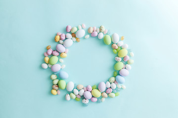 Happy Easter concept. Preparation for holiday. Easter candy chocolate eggs and jellybean sweets isolated on trendy pastel blue background. Simple minimalism flat lay top view copy space.