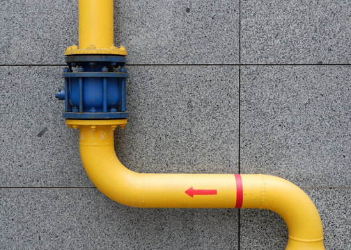 Yellow gas pipe on a background of a gray wall