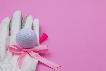Golf ball and pink ribbon are on pink background