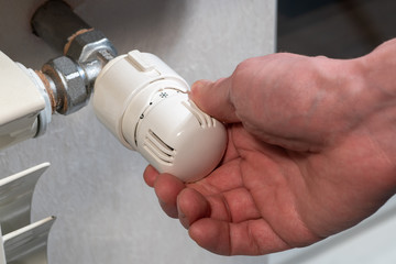 The male hand reduces the temperature on the thermostat to a minimum.