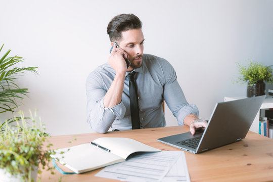 businessman working on laptop and talking on his phone at the same time