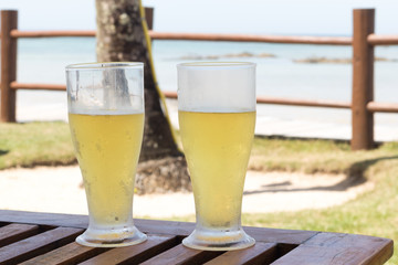 Two glasses of beer on the table at the beach.